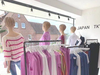 BSPNGN-FASHIONROOM_Bispingen.jpg Innenansicht des BSPNGN Fashionrooms in Bispingen, mit bunter Mode auf Kleiderstangen.