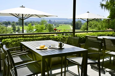 Kiekenstein-2024-219_Restaurant.jpg Gastronomie Außenterrasse mit Tischen, Stühlen und Sonnenschirmen, mit Blick über die Weser