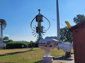 Deutsches Windkraftmuseum Windkraftmuseum mit alten Windturbinen und technischen Anlagen auf einer Wiese bei blauem Himmel.