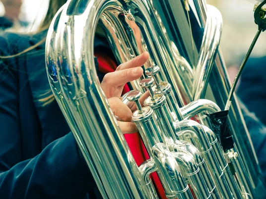 pexels-nikita-khandelwal-178978-788838.jpg Nahaufnahme eines glänzenden Blasinstruments, das von einer Person im blauen Anzug gespielt wird.