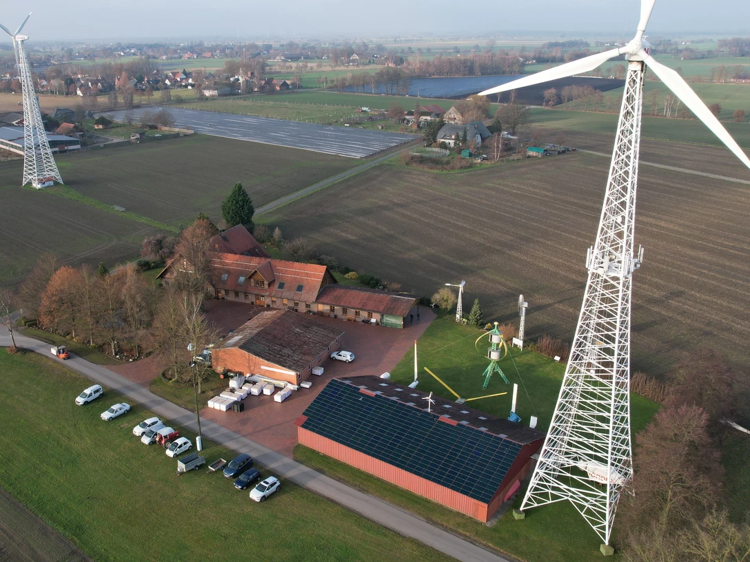 Drohnenaufnahme Windkraftmuseum Luftaufnahme des Windkraftmuseums mit großen Windrädern in ländlicher Umgebung und Solarpanels.