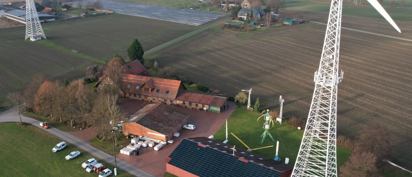 Drohnenaufnahme Windkraftmuseum Luftaufnahme des Windkraftmuseums mit großen Windrädern in ländlicher Umgebung und Solarpanels.