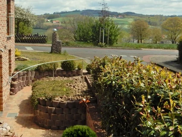 Ausblick von einer Ferienwohnung auf eine ländliche Straße, umgeben von Hecken und hügeliger Landschaft.