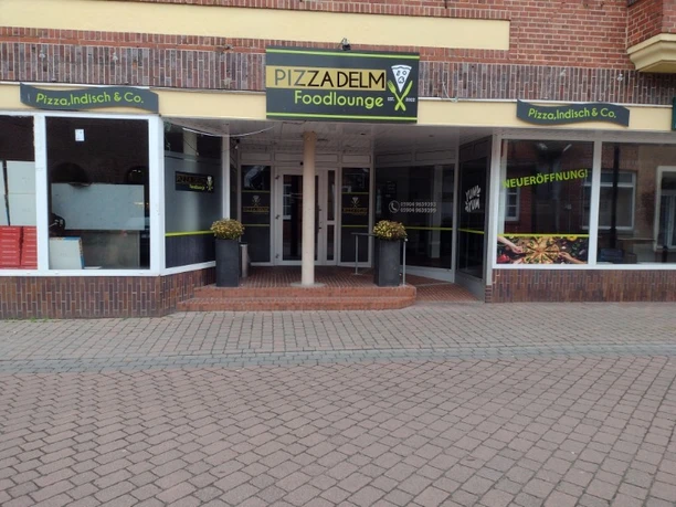 Pizza Delm.jpg Eingang der Pizzeria Pizza Delm mit Glasfront, gelbem Firmenschild und Hinweis auf Neueröffnung.