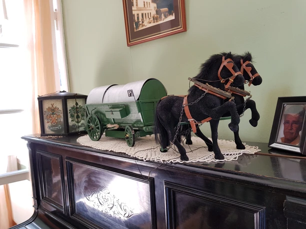 Pulvermuseum Ohl <p>Miniaturgespann mit schwarzem Pferd und grünem Wagen auf antikem Klavier.</p>