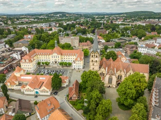 Luftaufnahme des Herforder Rathausplatzes mit der gotischen Kirche und umliegenden Gebäuden im Grünen.