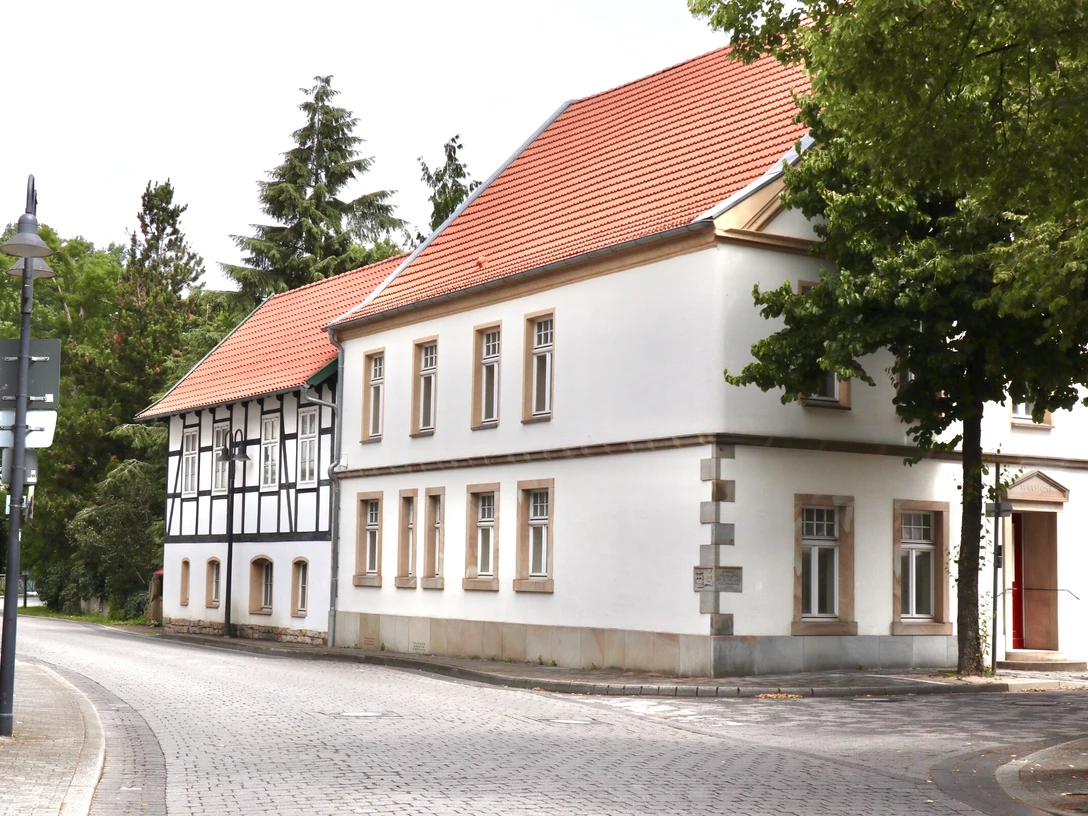 Verl Nr. 8 Straßenszene mit Fachwerkhaus und roten Dächern, umgeben von Bäumen und ruhiger Atmosphäre.