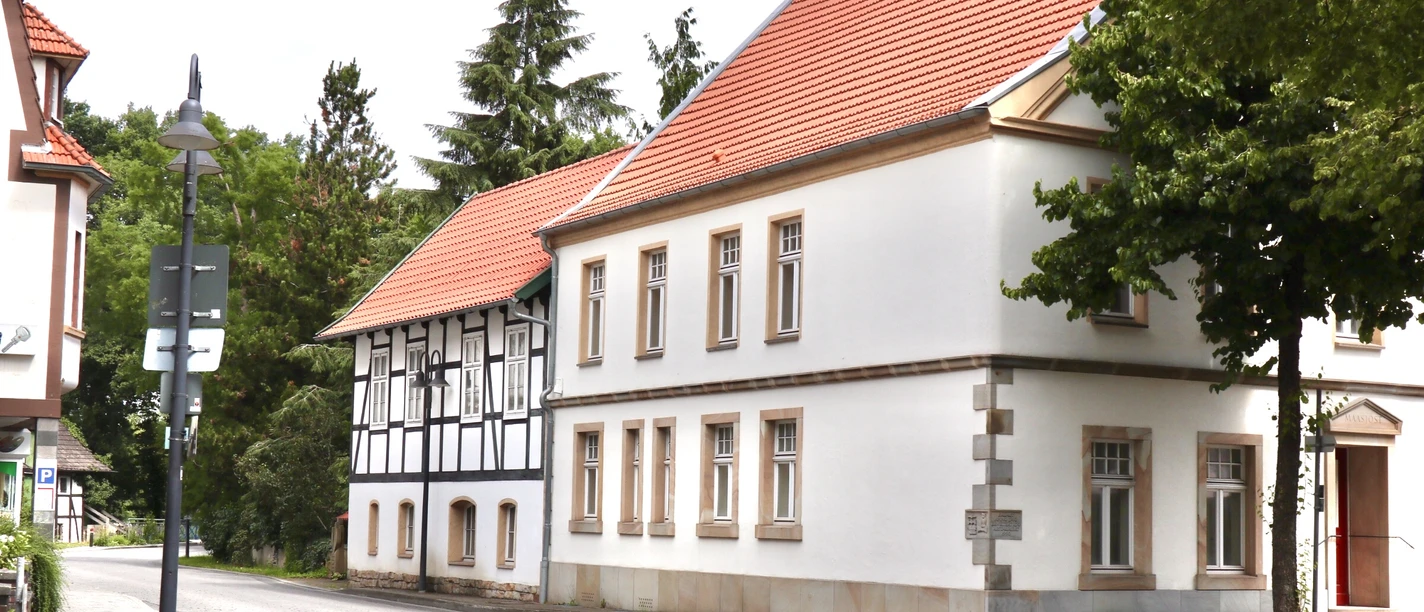 Verl Nr. 8 Straßenszene mit Fachwerkhaus und roten Dächern, umgeben von Bäumen und ruhiger Atmosphäre.