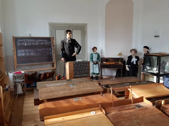 Historisches Klassenzimmer Historisches Klassenzimmer mit Schreibtischen, Schiefertafel, ausgestopften Figuren und antiken Lehrmitteln.