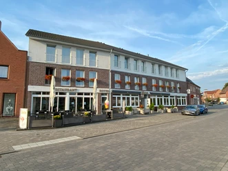 © Gemeinde Salzbergen Fassade des Restaurants und Hotels Bolte in Salzbergen mit Terrasse und blühenden Blumenkästen.