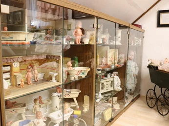 Spielzeugmuseum Vitrinen zeigen antikes Kinderspielzeug, Puppen und Badesets in einem Spielzeugmuseum.