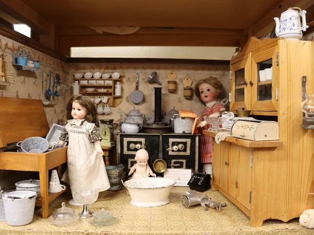 Spielzeugmuseum Historische Puppenküche mit Puppen und Miniaturen. Zu sehen sind Möbel, Geschirr und Utensilien.
