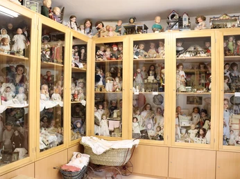 Spielzeugmuseum Regale voller antiker Puppen und Sammlerstücke in einem Ausstellungsraum mit Historienfokus.