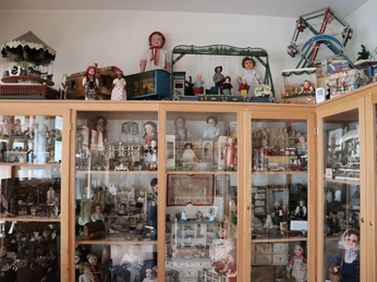 Spielzeugmuseum Schaukasten im Spielzeugmuseum mit Puppen, Miniaturmöbeln, Modellachterbahnen und Puppenhäusern.