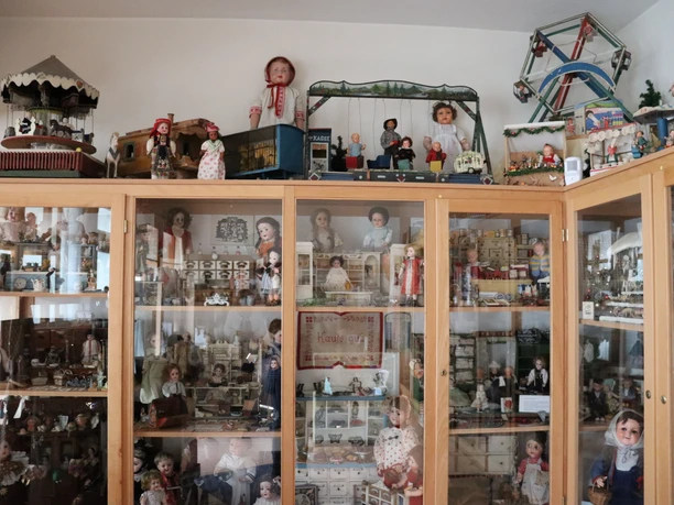 Schaukasten im Spielzeugmuseum mit Puppen, Miniaturmöbeln, Modellachterbahnen und Puppenhäusern.