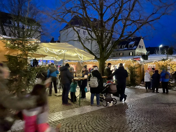 Menschen genießen eine winterliche Atmosphäre auf einem gemütlichen Weihnachtsmarkt in der Altstadt.