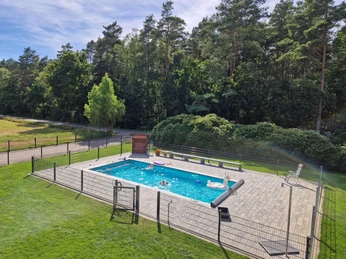 Ponyhof Hagedorn Ein Außenpool auf einer gepflasterten Fläche, umgeben von grüner Wiese und dichten Bäumen.An outdoor pool on a paved area, surrounded by green lawns and dense trees.En udendørs pool på et asfalteret område, omgivet af grønne plæner og tætte træer.Een buitenzwembad op een verhard terrein, omringd door groene gazons en dichte bomen.