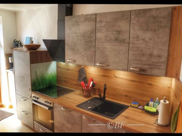 Fewo_Steinadler1-600x407.jpg Moderne Küche mit Holzdetails, Spüle, Ceran-Kochfeld, Backofen und Dunstabzug.