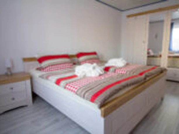 IMG_7942-200x133.jpg Zwei Einzelbetten mit rot-weiß karierten Bettdecken in einem hellen Schlafzimmer mit laminierten Holzboden.