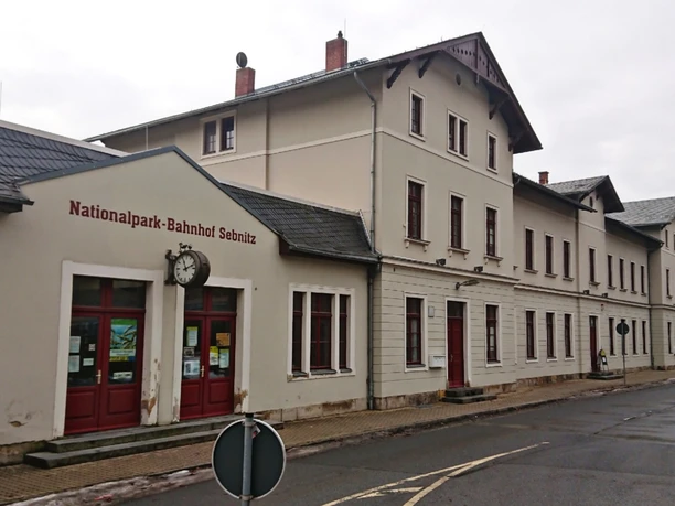 Nationalparkbahnhof Sebnitz Nationalpark-Bahnhof Schmilka, mehrstöckiges Gebäude mit roten Türen und Uhr an der Fassade.
