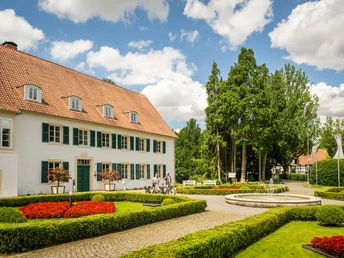 Preußisch-Oldendorf- Kurpark Bad Holzhausen Kurpark Bad Holzhausen mit historischem Gebäude, Brunnen, gepflegten Hecken und blühenden Beeten.
