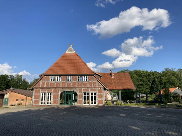 SpeicherKaffee Rotes Backsteinhaus mit rotem Ziegeldach und dunkelgrüner Eingangstür vor blauem Himmel.