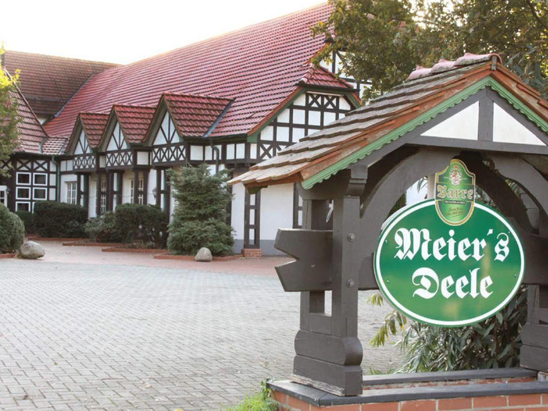 Traditionelles Fachwerkhaus mit rotem Ziegeldach in Stemwede, Schild zeigt Schriftzug "Meier's Deele".