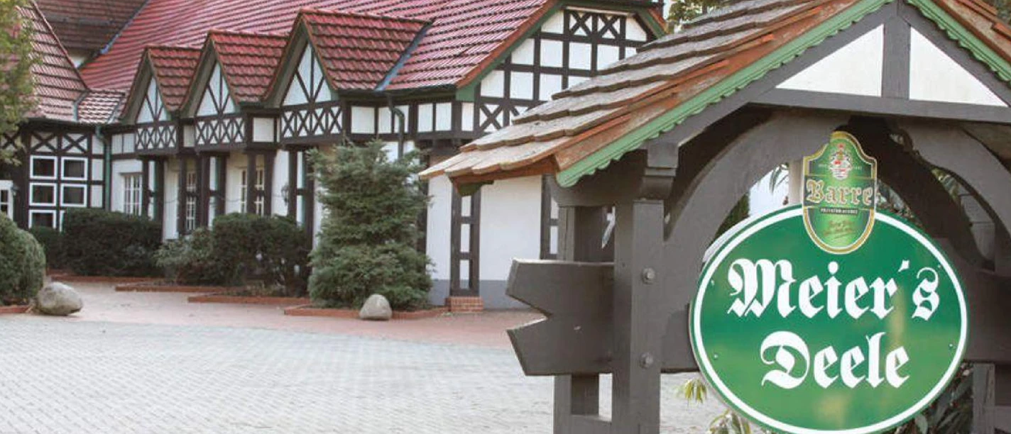 Meiers_Deele.jpg Traditionelles Fachwerkhaus mit rotem Ziegeldach in Stemwede, Schild zeigt Schriftzug "Meier's Deele".