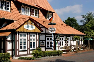 Marktschänke.jpg Ein Fachwerk-Gebäude mit Terrassensitzplätzen, deutschem Schild "Marktschänke" und rot gedecktem Dach.