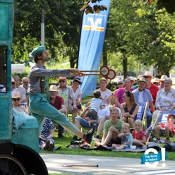 Herford-Mein Sommer Meine Stadt-Pro Herford GmbH.jpg Ein Jongleur in Aktion, umgeben von einem aufmerksamen Sommerpublikum im Park.