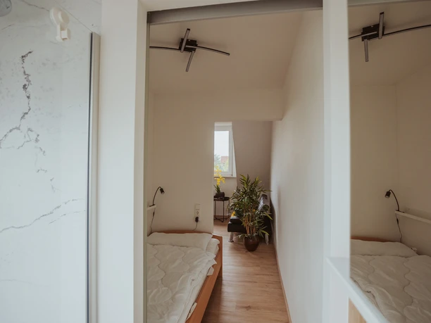 FeWo Hille Krysiak Helles Schlafzimmer mit zwei Einzelbetten, modernem Interieur und Fenster mit Tageslicht.