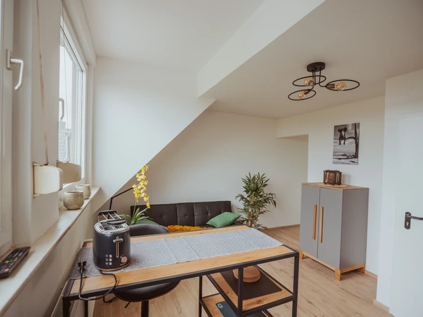 FeWo Hille Krysiak Moderne Ferienwohnung mit stilvoller Einrichtung, hellen Wänden und komfortablen Sitzmöglichkeiten.