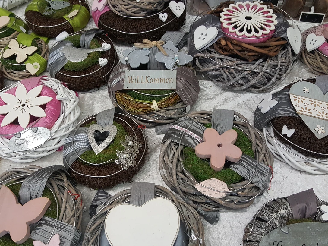 Kunsthandwerkermarkt Bunte Handwerkskränze mit Holzblumen, Herzen und Schmetterlingen ausgestellt auf einem Marktstand