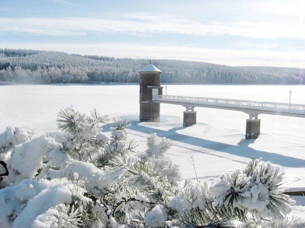 Verschneite Wasserfläche der Talsperre Cranzahl mit Turm