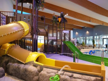 aquaferrum Ein modernes Hallenbad mit Rutschen und Wasserbereich. Holzdecken und Pflanzen schaffen eine freundliche Atmosphäre.A modern indoor pool with slides and water area. Wooden ceilings and plants create a friendly atmosphere.En moderne indendørs pool med rutsjebaner og vandområde. Trælofter og planter skaber en venlig atmosfære.Een modern binnenzwembad met glijbanen en waterzone. Houten plafonds en planten zorgen voor een vriendelijke sfeer.