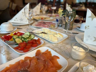 Ein Frühstückstisch mit Lachs, Gemüse, Käsescheiben und elegant gefalteten Servietten.