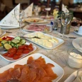 Frühstück_Schlosskrug2CCBYSA_Teutoburger Wald_Stadt_Schloß Holte-Stukenbrock.jpg Ein Frühstückstisch mit Lachs, Gemüse, Käsescheiben und elegant gefalteten Servietten.