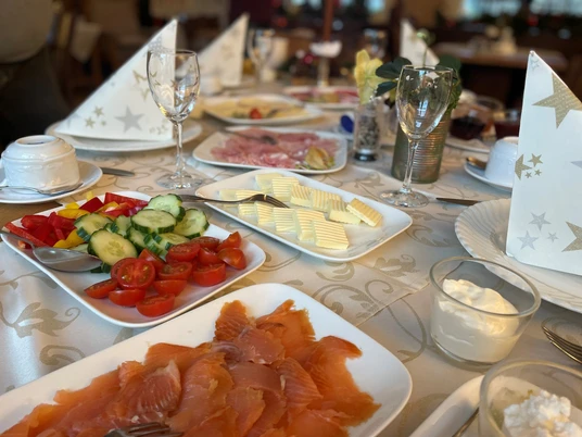 Frühstück_Schlosskrug2CCBYSA_Teutoburger Wald_Stadt_Schloß Holte-Stukenbrock.jpg Ein Frühstückstisch mit Lachs, Gemüse, Käsescheiben und elegant gefalteten Servietten.