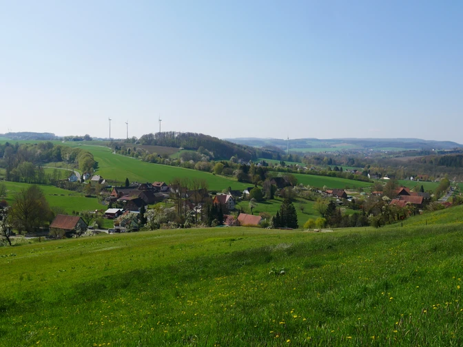 Grüne Hügellandschaft des Extertals bei Bremke, gesprenkelt mit Windrädern und kleinen Dörfern.