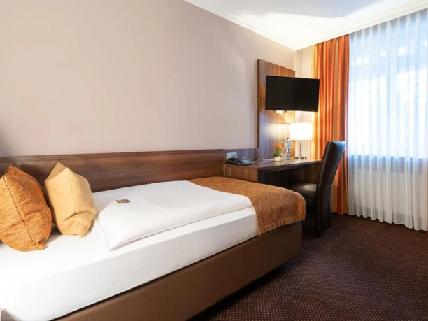 Business Einzelzimmer im Hotel im Park, Haan Einzelzimmer mit Schreibtisch, Flachbildfernseher und Bett, modern eingerichtet und gut beleuchtet.