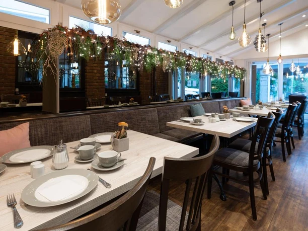 Frühstücksraum im Hotel im Park, Haan Modern eingerichteter Frühstücksraum mit Holzsitzmöbeln und gedeckten Tischen, dekoriert mit Lichterketten.