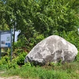Findling am Theikenmeer, Werlte ©Naturpark Hümmling (1).jpg Großer Findling neben Infotafel am Wegesrand, umgeben von grünen Büschen und freiem Feld.
