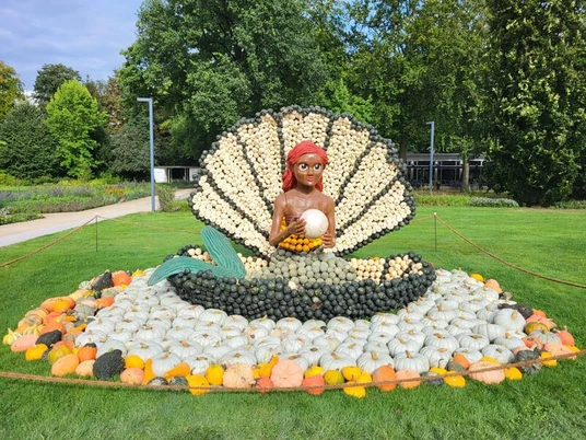 Eine Skulptur von Arielle, gefertigt aus Kürbissen, präsentiert eine Meerjungfrau in einer geöffneten Muschel.