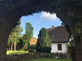 Blick durch einen Steinbogen auf Häuser der Gutshofanlage Maygadessen
