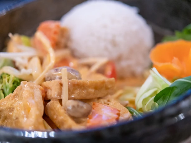 Close-up of a curry dish with tofu, vegetables and rice