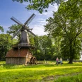 Hüvener Mühle – Radfahren Hümmling ©Emsland Tourismus GmbH (2).jpg Zwei Radfahrende auf einem grünen Weg neben der historischen Hüvener Mühle im Emsland.