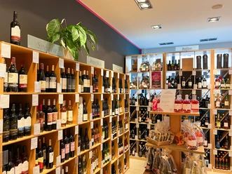 Barrique: Weinregal In einem Geschäft sind hohe Regale an den Wänden, die mit vielen verschiedenen Weinflaschen gefüllt sind.
