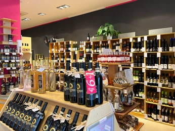 In einem Geschäft sind hohe Regale an den Wänden, die mit vielen verschiedenen Weinflaschen gefüllt sind.