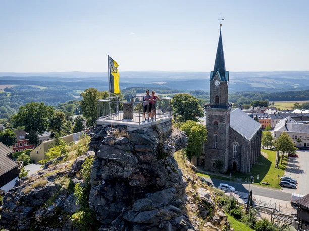 Kammweg Etappe 14 - Alter Söll Schöneck Aussichtsplattform über Schöneck mit Panoramablick, Kirche im Hintergrund, Sonnenschein.
