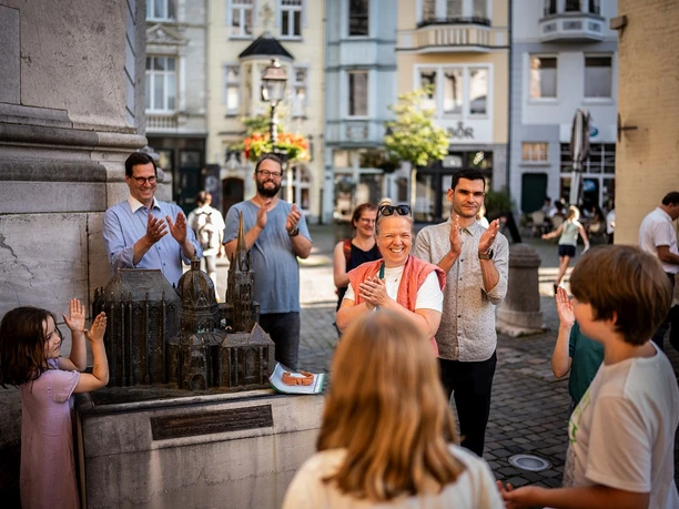 Eine fröhliche Gruppe applaudiert um ein detailgetreues Modell des Doms.